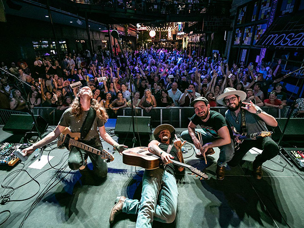 Jackson Dean and his band laying down on stage with the crowd behind them